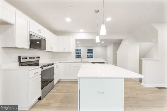 a kitchen with stainless steel appliances kitchen island a white cabinets sink and stove