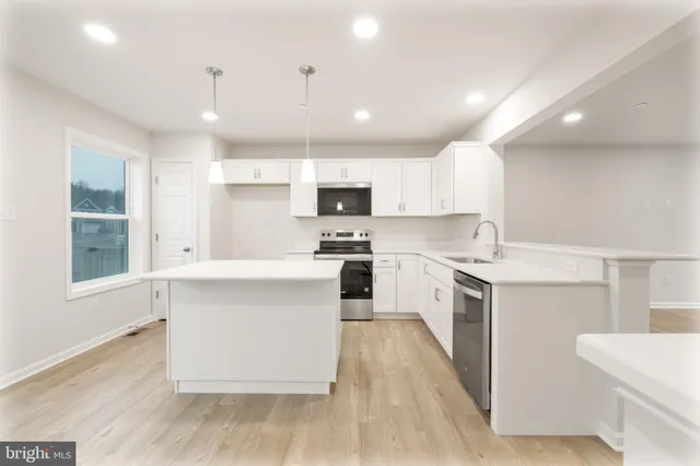 a large kitchen with granite countertop a large counter top a sink stainless steel appliances and cabinets