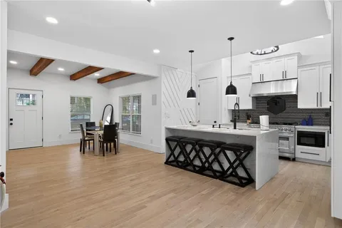 a kitchen with stainless steel appliances a table and chairs in it