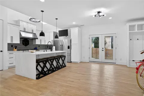 a kitchen with stainless steel appliances a stove top oven a sink a refrigerator white cabinets and wooden floor