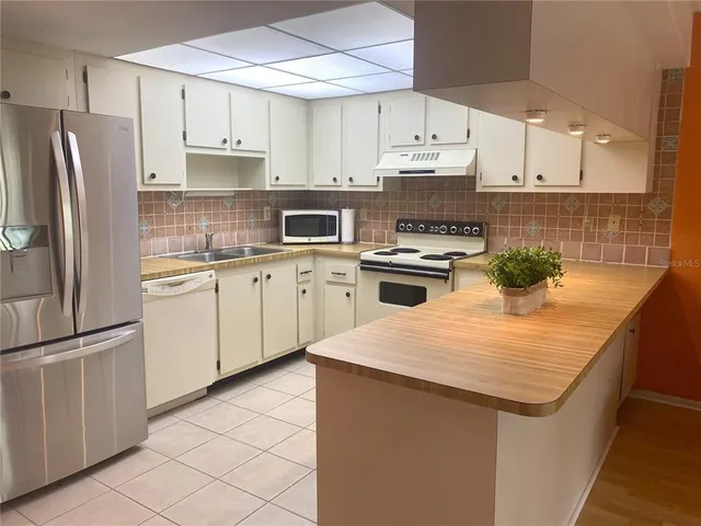 a kitchen with stainless steel appliances granite countertop a sink stove refrigerator and cabinets