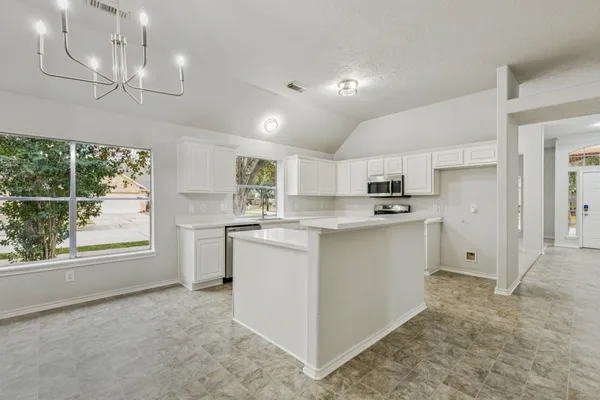 a kitchen with white cabinets and window