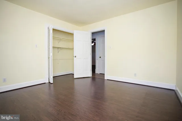 an empty room with wooden floor & closet and windows
