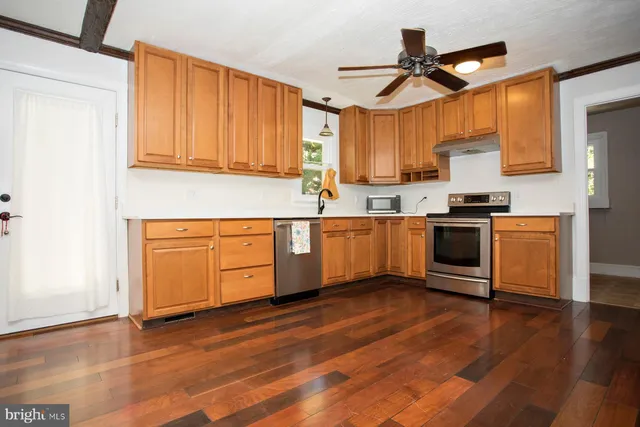 a kitchen with stainless steel appliances granite countertop a sink cabinets and wooden floor