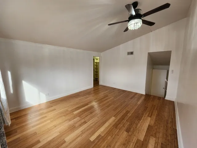 an empty room with wooden floor fan and windows