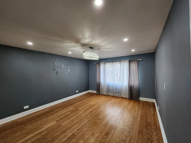 a view of an empty room with wooden floor and window