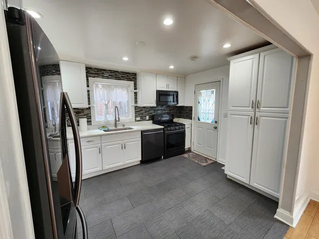 a kitchen with refrigerator a sink and white cabinets