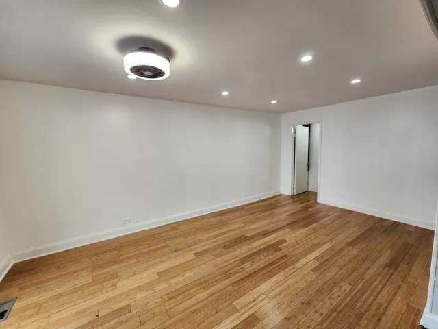 an empty room with wooden floor and natural light
