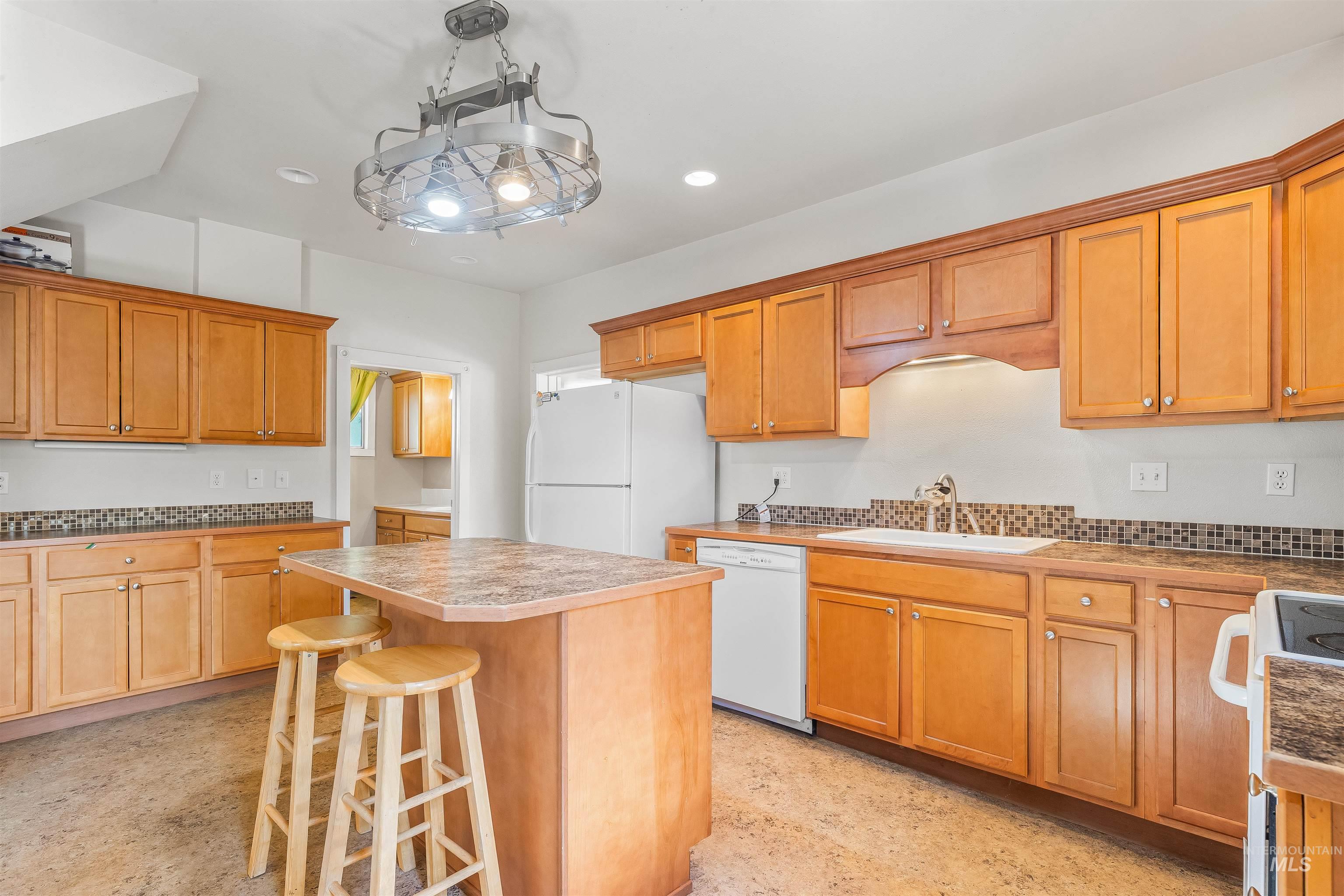 815 2nd Street Asotin, WA 99402 - Photo 11 of 50 Kitchen featuring white appliances, a kitchen breakfast bar, a kitchen island, recessed lighting, and brown cabinetry