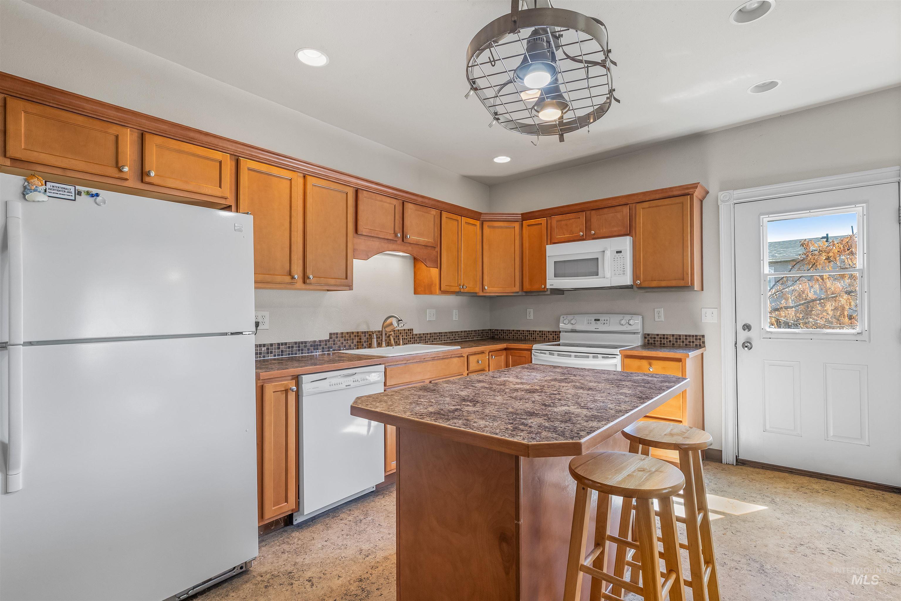 815 2nd Street Asotin, WA 99402 - Photo 13 of 50 Kitchen with white appliances, a center island, recessed lighting, a kitchen bar, and dark countertops
