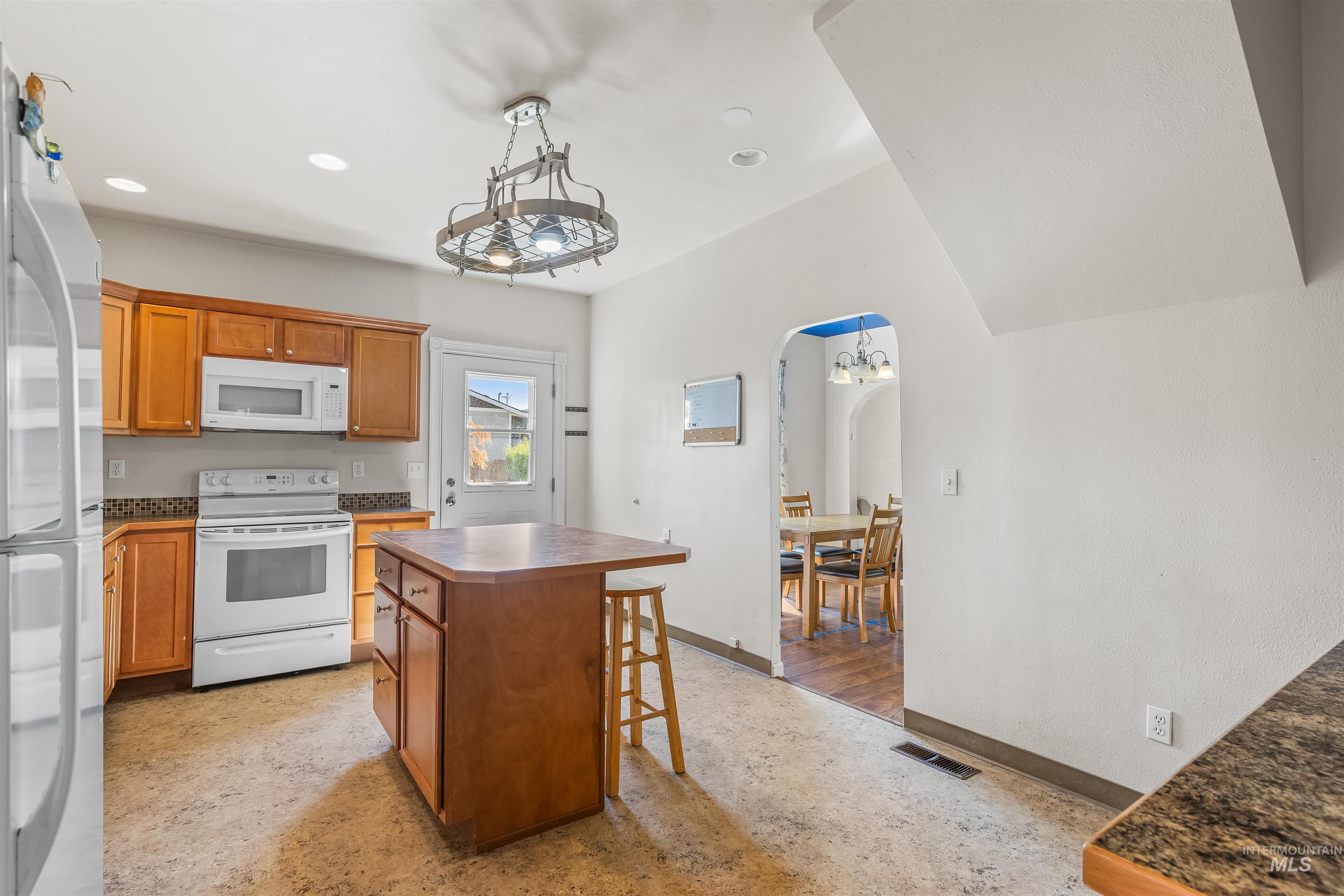 815 2nd Street Asotin, WA 99402 - Photo 15 of 50 Kitchen featuring white appliances, arched walkways, concrete floors, a kitchen island, and a breakfast bar area