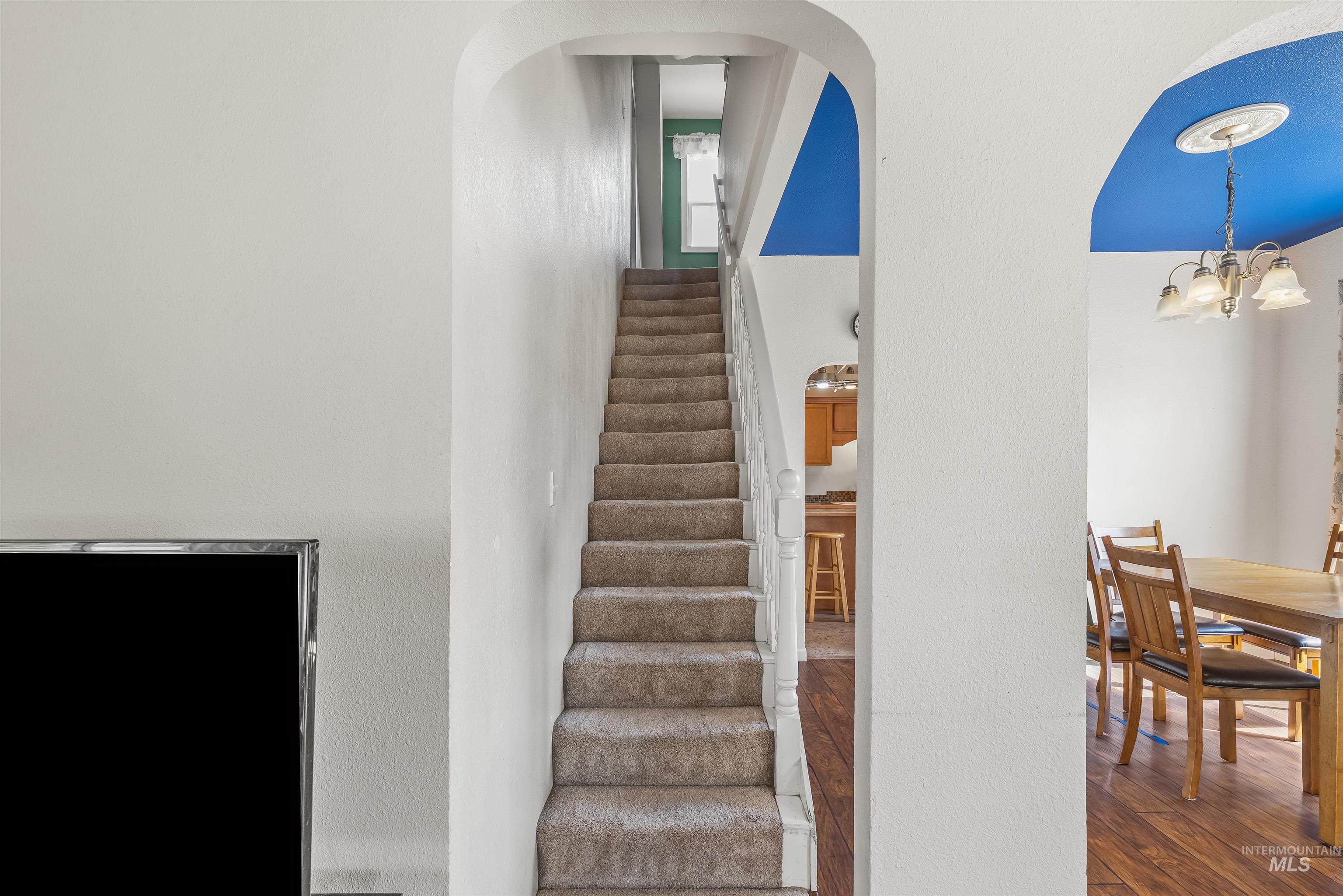 815 2nd Street Asotin, WA 99402 - Photo 20 of 50 Staircase featuring wood finished floors, a chandelier, arched walkways, and a textured wall