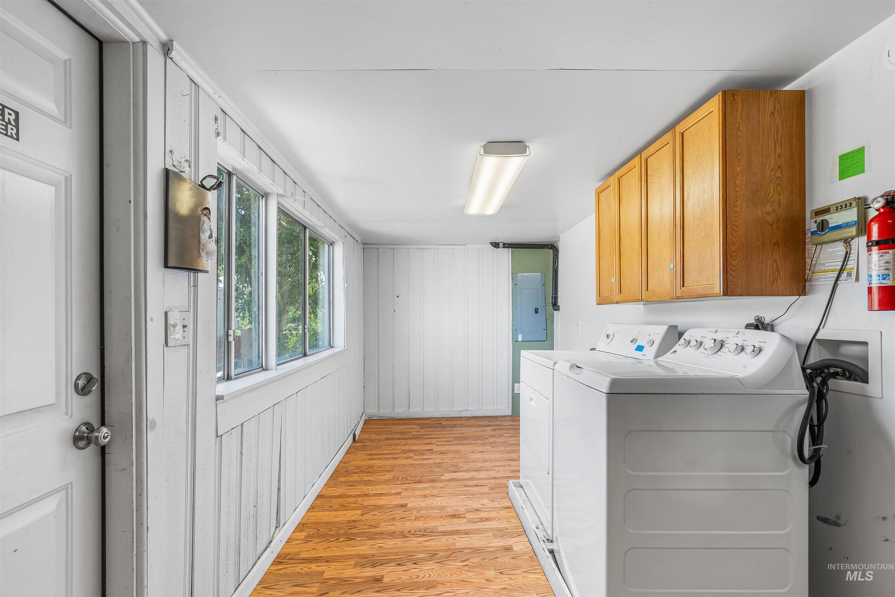 815 2nd Street Asotin, WA 99402 - Photo 33 of 50 Laundry room with light wood-style floors, washer and dryer, electric panel, and cabinet space