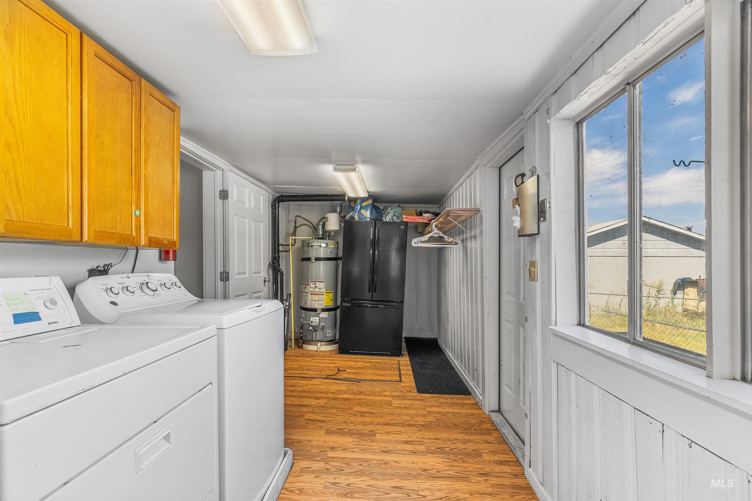 815 2nd Street Asotin, WA 99402 - Photo 34 of 50 Washroom featuring cabinet space, washing machine and clothes dryer, light wood finished floors, and water heater