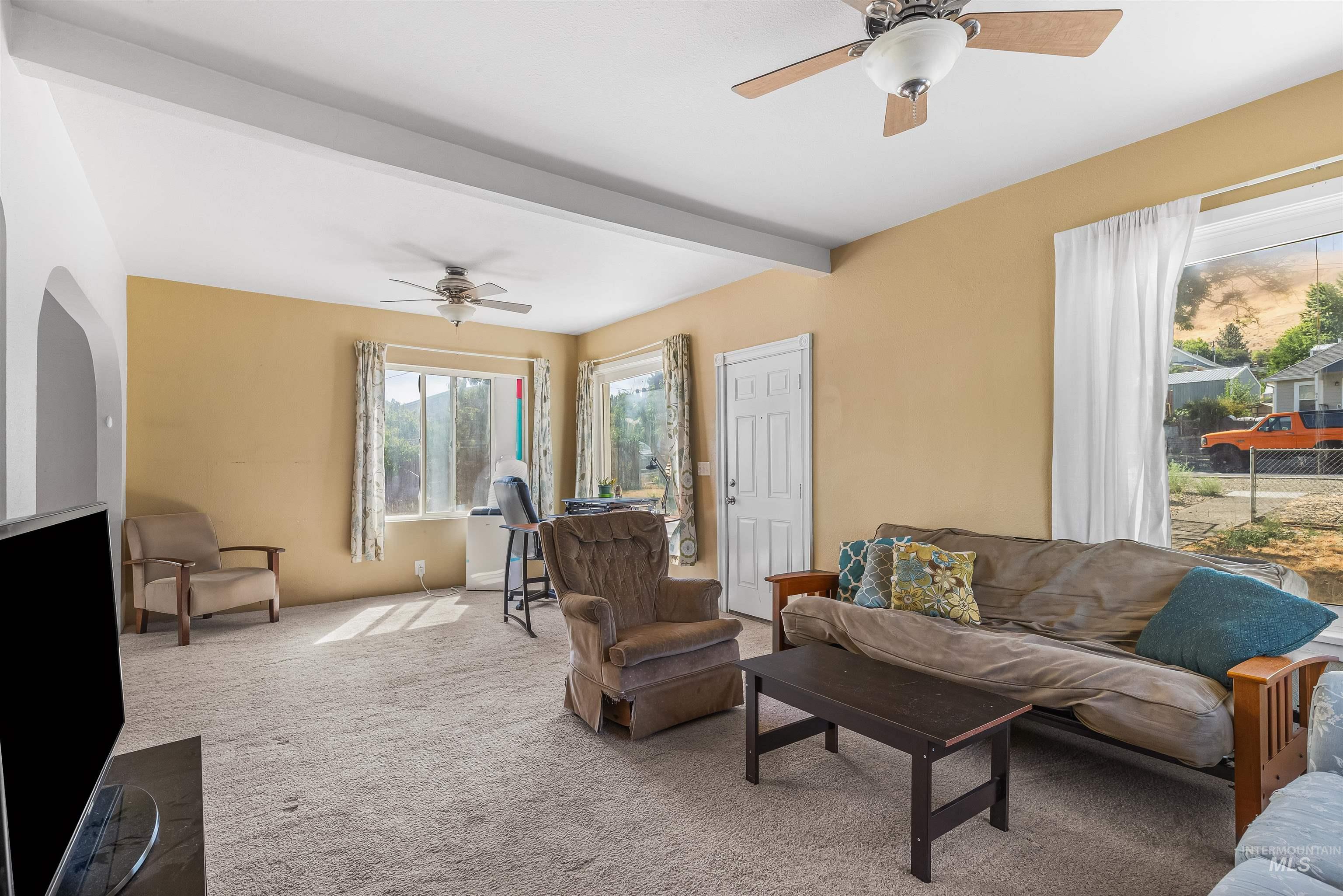 815 2nd Street Asotin, WA 99402 - Photo 5 of 50 Living room with a ceiling fan, carpet flooring, beamed ceiling, and arched walkways