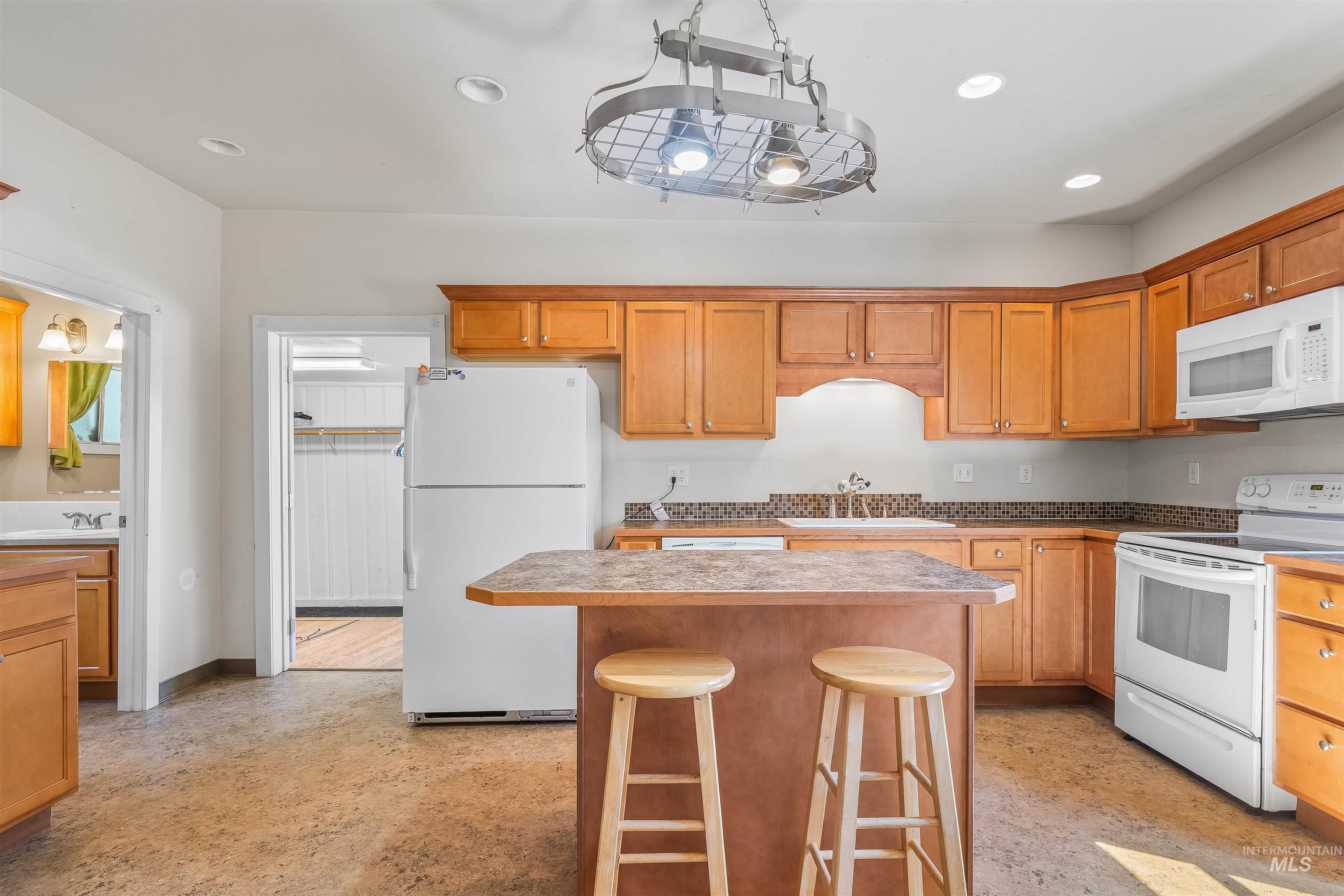 815 2nd Street Asotin, WA 99402 - Photo 10 of 50 Kitchen featuring white appliances, recessed lighting, a kitchen island, a breakfast bar, and finished concrete flooring