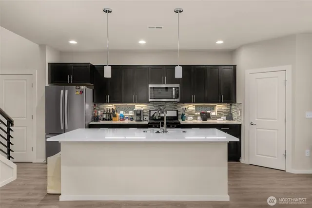 a large kitchen with stainless steel appliances kitchen island a large counter top and wooden floors