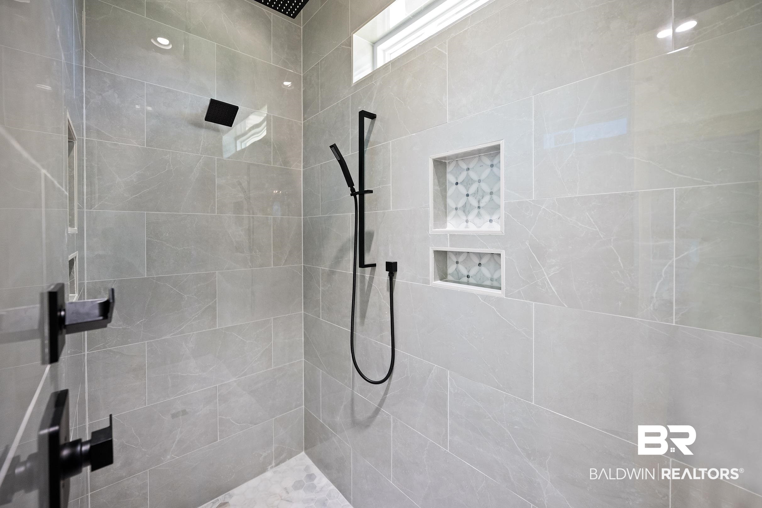 13111 Gopher Court Elberta, AL 36530 - Photo 17 of 41 Shower with large format light gray tile, black matte fixtures, and built-in niches with decorative tile accents