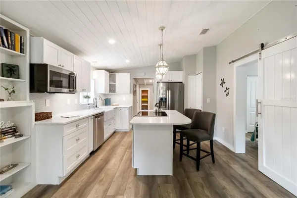 a kitchen with stainless steel appliances a dining table chairs a sink a refrigerator and cabinets