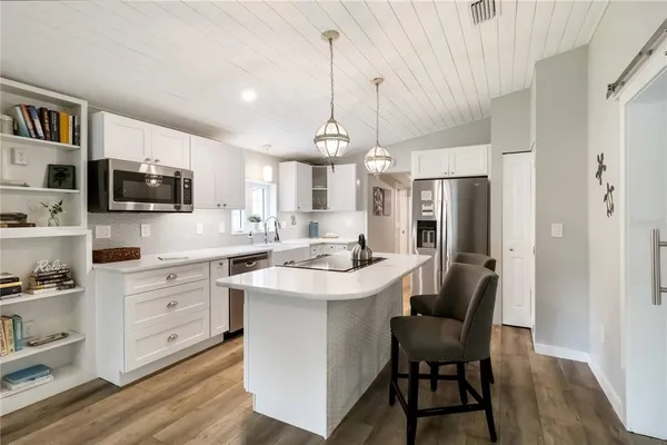 a kitchen with stainless steel appliances kitchen island granite countertop a table chairs refrigerator and microwave