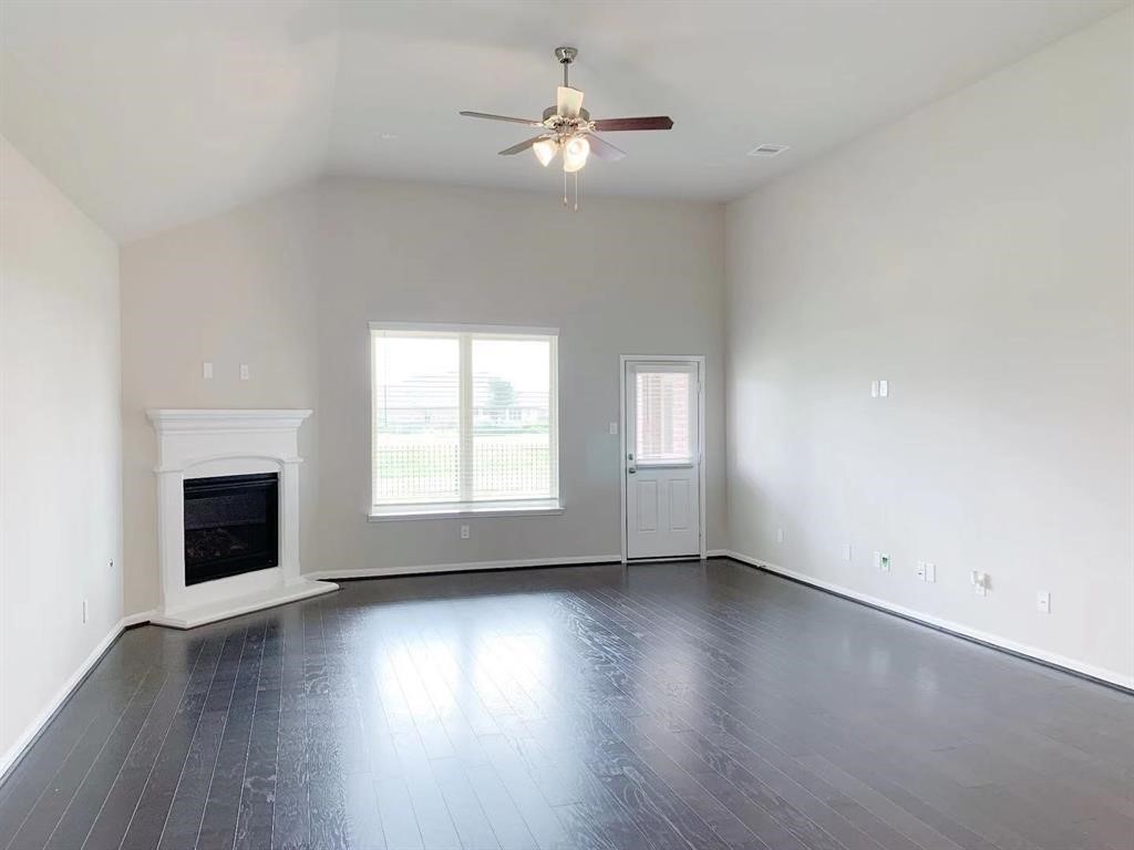 29026 Endeavor River Road Katy, TX 77494 - Photo 10 of 27 an empty room with wooden floor fireplace and windows