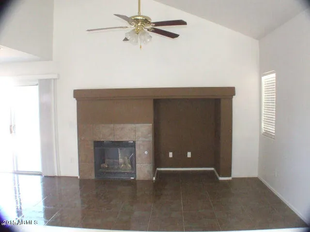 an empty room with fan and a fireplace