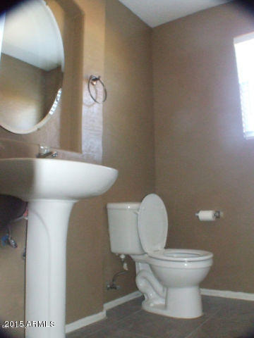 718 West Spruell Avenue Coolidge, AZ 85128 - Photo 8 of 15 a white toilet sitting next to a bathroom sink and a mirror