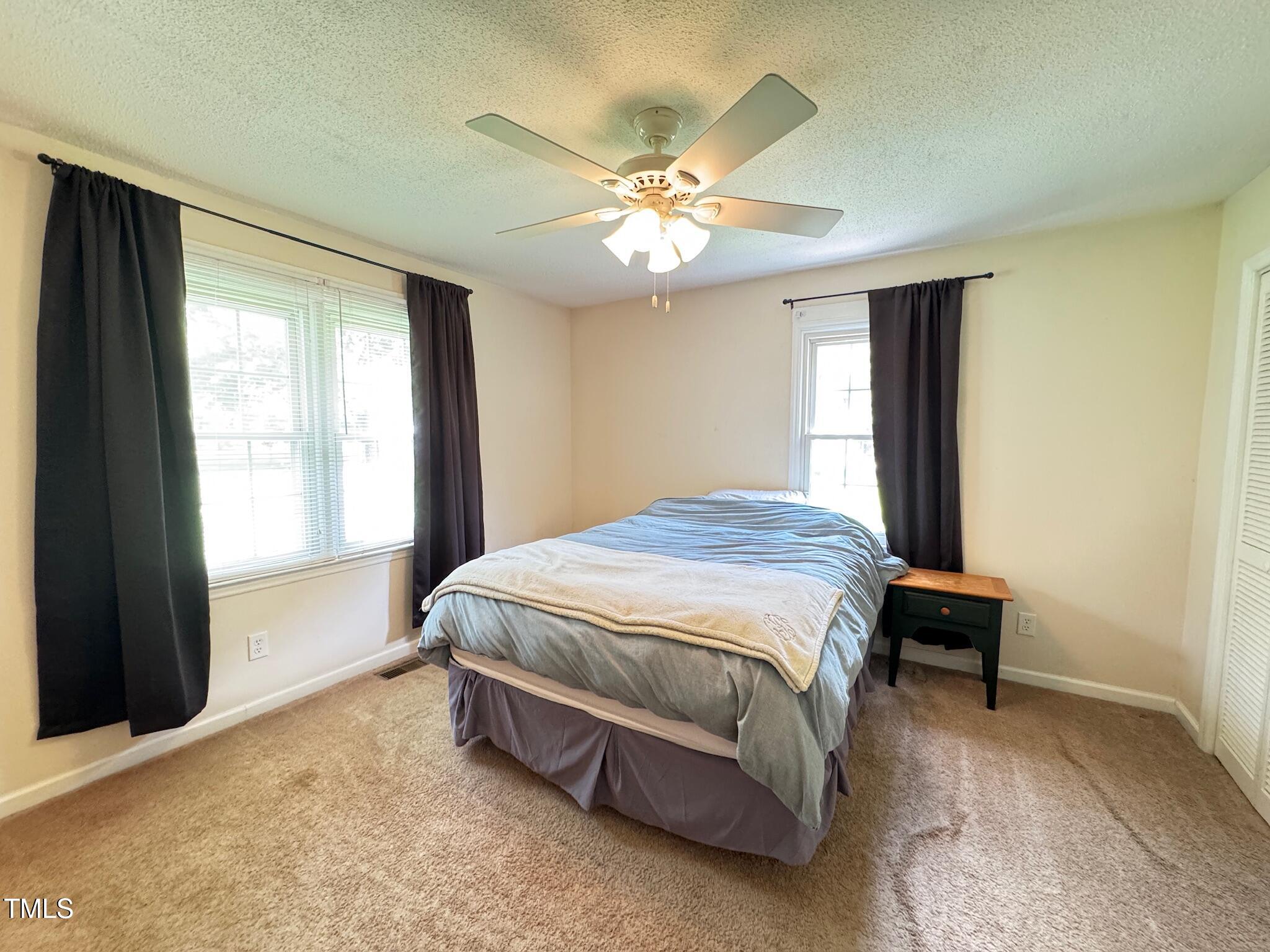 2229 Lizard Lick Road Zebulon, NC 27597 - Photo 11 of 57 a spacious bedroom with a bed and a chandelier