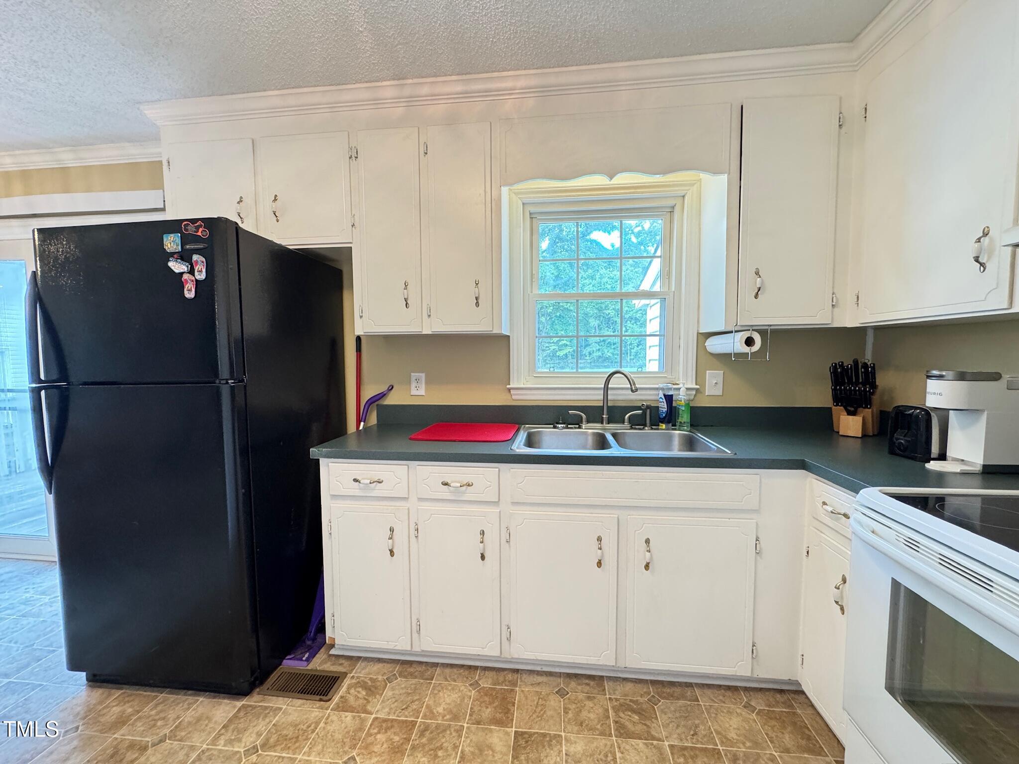 2229 Lizard Lick Road Zebulon, NC 27597 - Photo 30 of 57 a kitchen with a refrigerator and cabinets