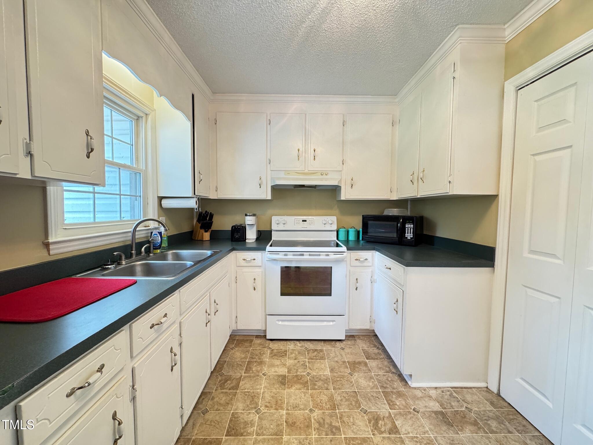 2229 Lizard Lick Road Zebulon, NC 27597 - Photo 31 of 57 a kitchen with granite countertop a stove top oven sink and cabinets