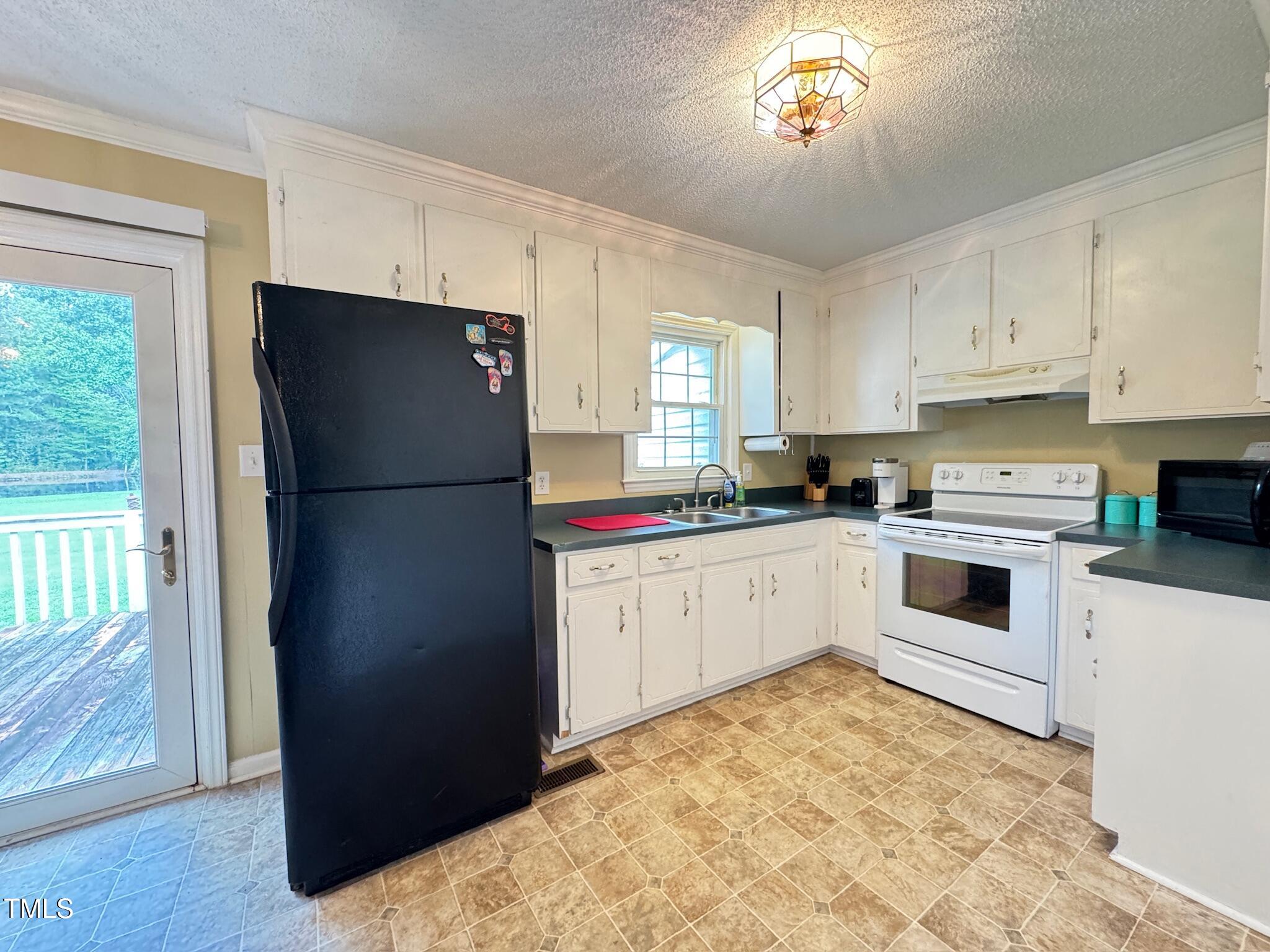 2229 Lizard Lick Road Zebulon, NC 27597 - Photo 32 of 57 a kitchen with a refrigerator and a stove top oven