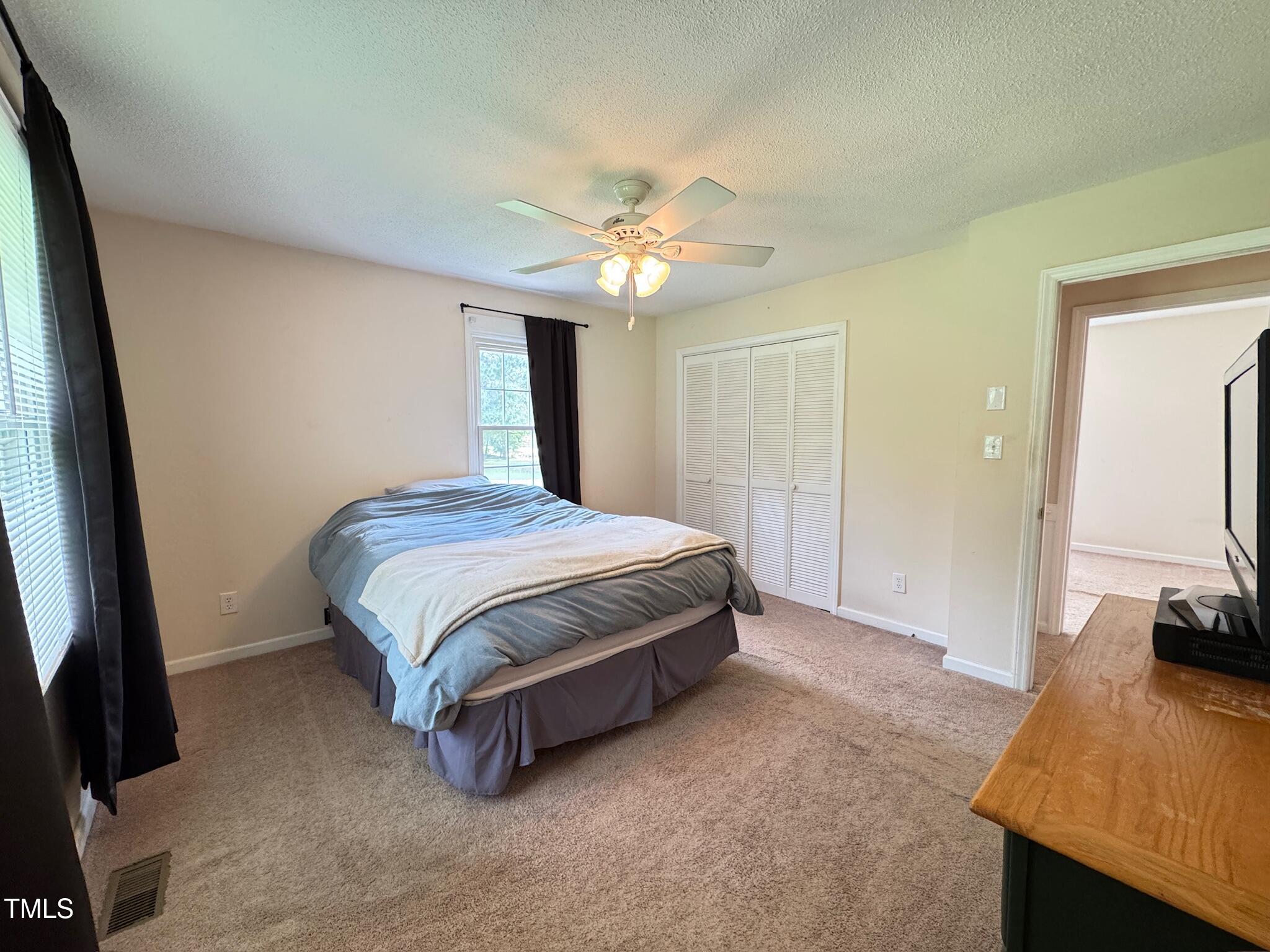 2229 Lizard Lick Road Zebulon, NC 27597 - Photo 10 of 57 a bedroom with a bed and a flat tv screen on dresser