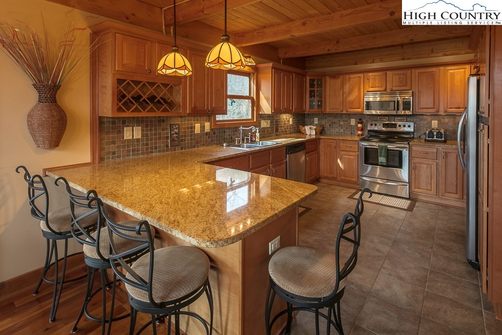 272 Locust Road Newland, NC 28657 - Photo 23 of 46 a kitchen with stainless steel appliances granite countertop a sink a stove and chairs