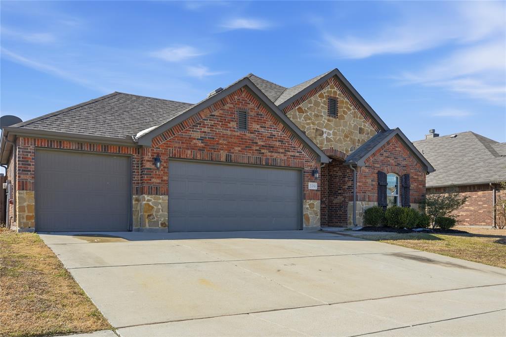 View of front of house featuring stone siding, concrete driveway, an attached garage, and brick siding