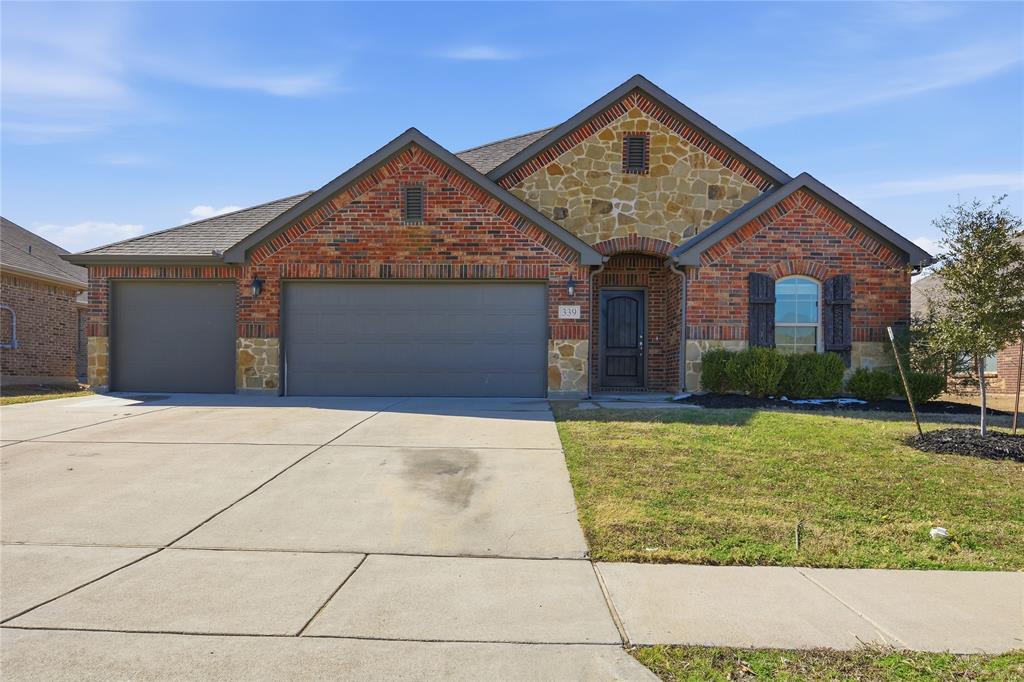 339 Blanco Drive Forney, TX 75126 - Photo 2 of 24 View of front of house with stone siding, driveway, an attached garage, and a front yard