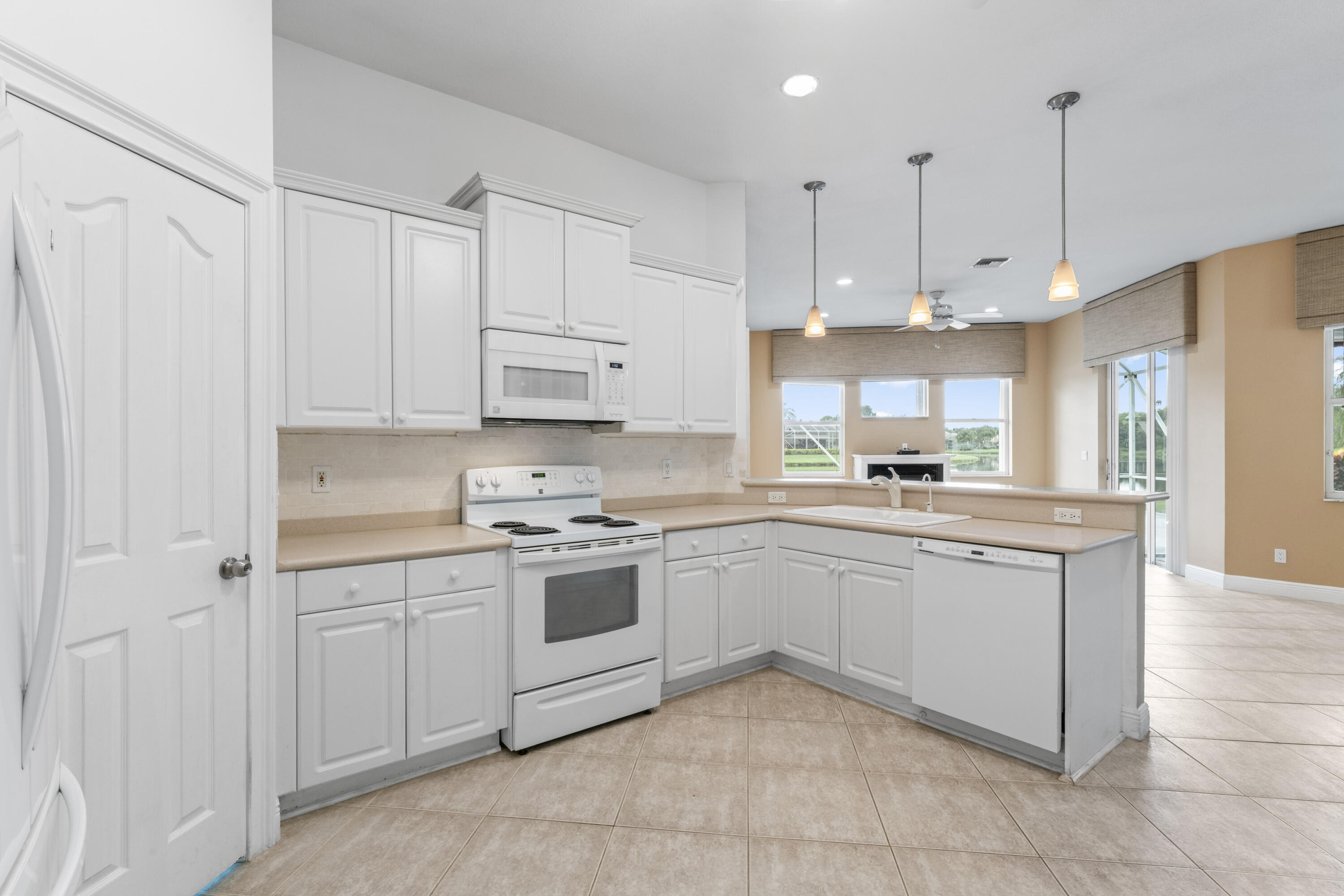 918 Southwest Blue Stem Way Stuart, FL 34997 - Photo 12 of 47 a kitchen with kitchen island granite countertop white cabinets white stainless steel appliances with a sink and dishwasher