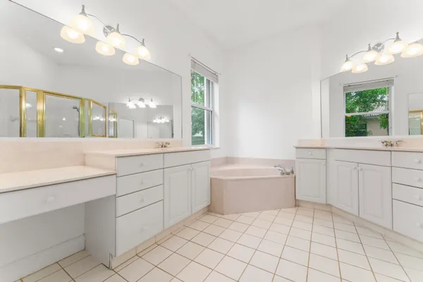 a large white bathroom with a large tub sink vanity and granite