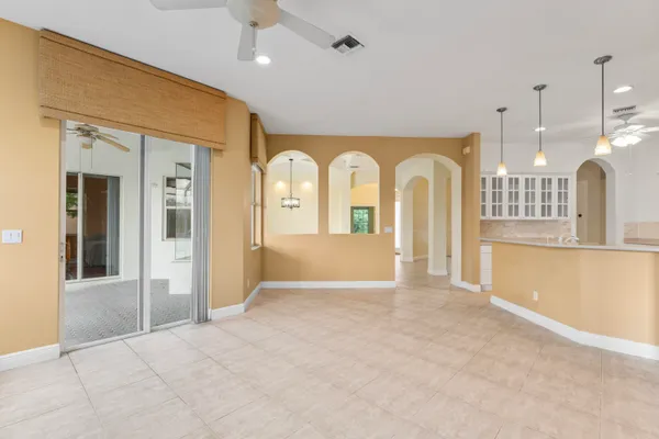 a view of an empty room with kitchen and wooden floor