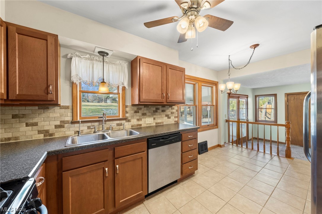 227 South Messner Road New Franklin, OH 44319 - Photo 26 of 44 Kitchen featuring hanging light fixtures, ceiling fan with notable chandelier, stainless steel appliances, and tasteful backsplash