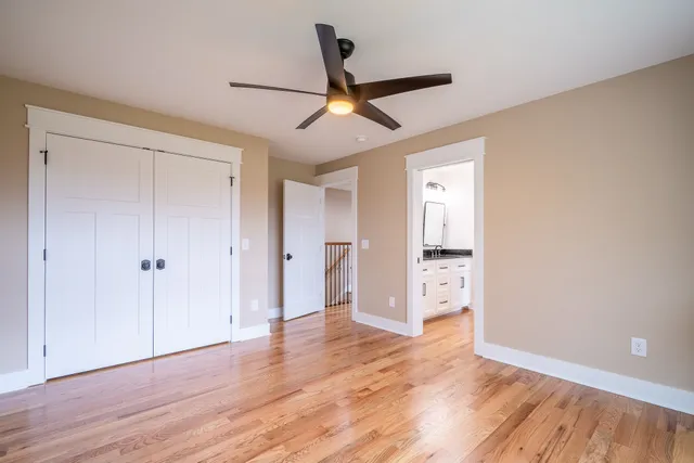 an empty room with wooden floor ceiling fan and windows