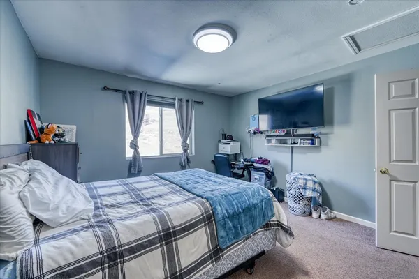 a bedroom with a bed and a flat tv screen on the dresser