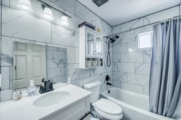 a bathroom with a bathtub shower sink vanity mirror and toilet