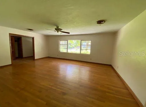 a view of an empty room with wooden floor and a window