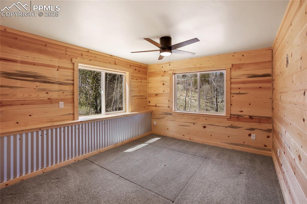 621 Yorktown Road Cripple Creek, CO 80813 - Photo 12 of 29 Primary bedroom with pine paneling, metal accents, carpet and ceiling fan