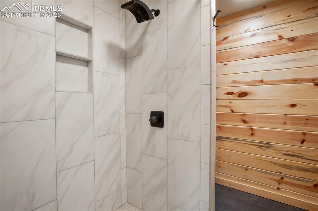 621 Yorktown Road Cripple Creek, CO 80813 - Photo 15 of 29 Bathroom featuring a tile shower and wood walls