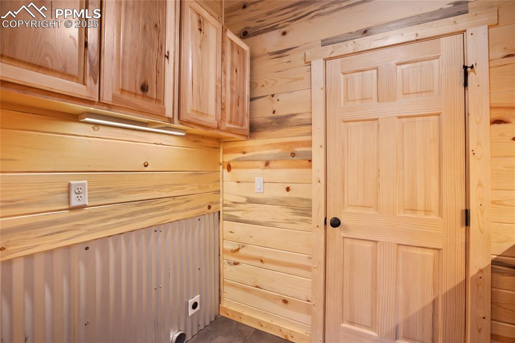 621 Yorktown Road Cripple Creek, CO 80813 - Photo 21 of 29 Laundry area featuring cabinet space, hookup for an electric dryer, and wooden walls