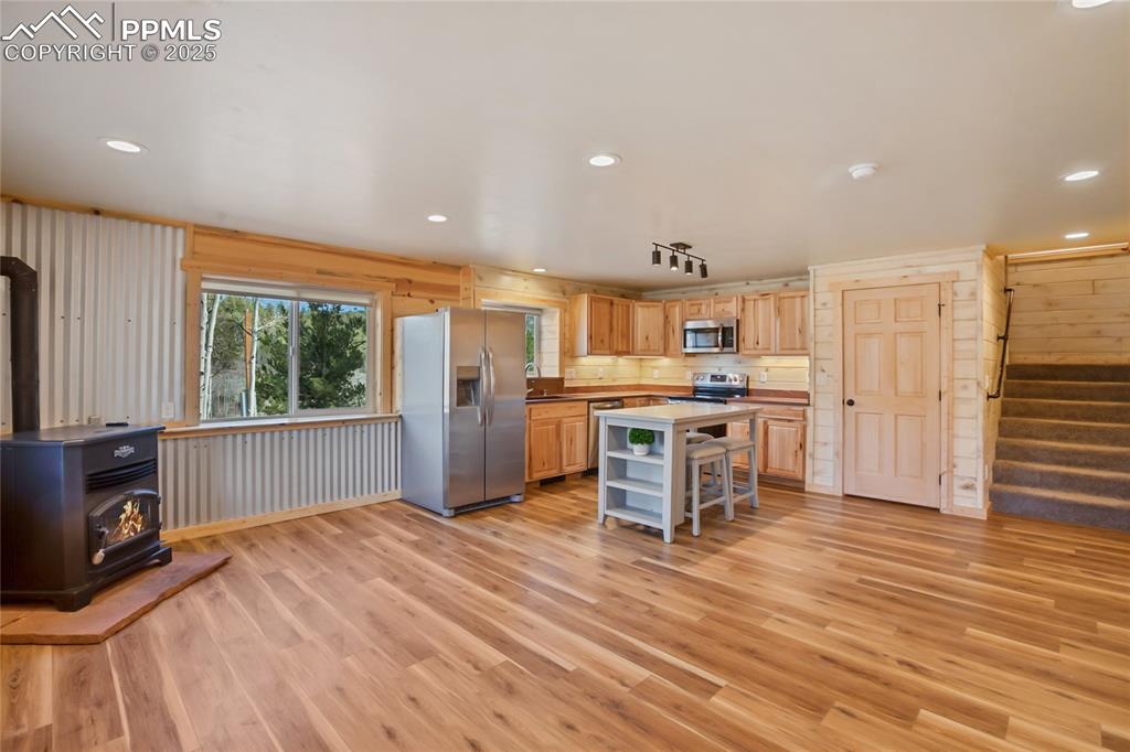 621 Yorktown Road Cripple Creek, CO 80813 - Photo 9 of 29 Kitchen with appliances with stainless steel finishes, pellet stove, LVP flooring, and a kitchen island
