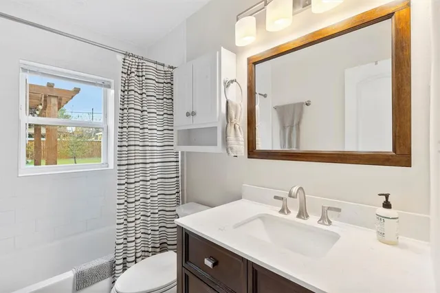 a bathroom with a sink a toilet a mirror and shower