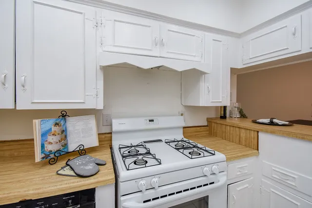 a kitchen with white cabinets and stove