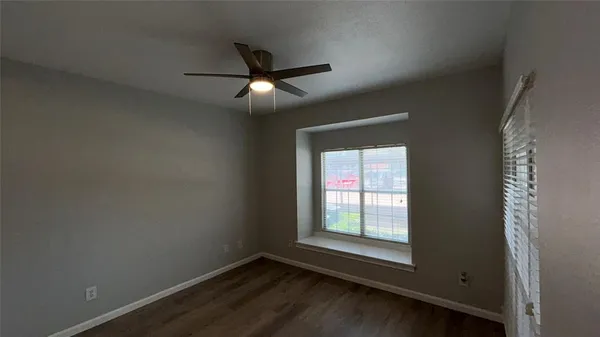 an empty room with wooden floor fan and windows